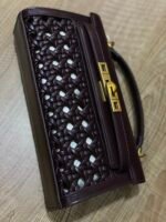 JW PEI Noor Top Handle Bag in dark red is a vegan leather bag featuring gold hardware and a woven design. - Image 7